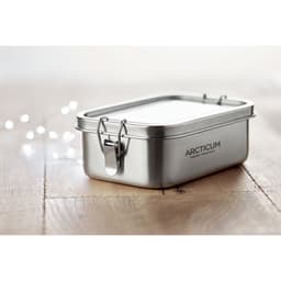 A stainless steel lunchbox with a lid and a metal clasp, resting on a wooden surface. The product features a logo.