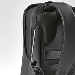 A black backpack with a zippered pocket, featuring an accessible slot for a device like a phone or tablet.