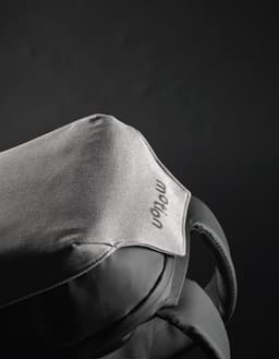 A grey backpack featuring a sleek design with a soft fabric top and a logo on the surface.