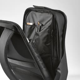 A black backpack features multiple compartments, including pockets for pens and a drink bottle. It has a sleek design and a logo.