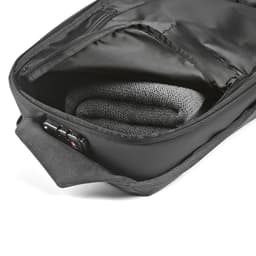 A black backpack with an inner compartment containing a rolled grey fabric, featuring a TSA lock and anticut material.