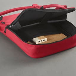 A red backpack with a spacious interior featuring a cork base and a zippered compartment, also displaying a logo.