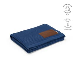A folded navy blue Giotto blanket with a brown customised patch, featuring a textured pattern.