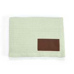 A mint green blanket with a textured pattern and a brown customizable patch.