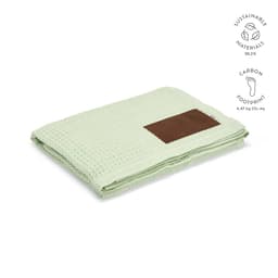 A light green Giotto blanket made of sustainable materials with a brown customizable patch.
