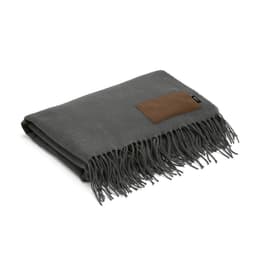 A grey blanket featuring fringed edges and a customisable patch, folded neatly.