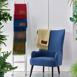 A stack of colourful Lichtenstein blankets in red, blue, green, grey, and beige displayed alongside a blue armchair.