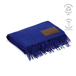 A blue Lichtenstein blanket made from sustainable materials, featuring a customisable patch and fringed edges.