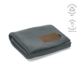 A grey blanket made from sustainable materials, featuring a customisable brown patch and a logo.