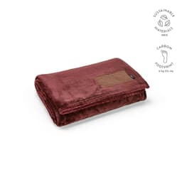 A maroon blanket made from sustainable materials, featuring a customisable patch and a soft texture.
