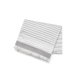 A folded blanket in white with textured patterns and thin black stripes, featuring fringe at the edge.