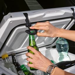A cooler with a white exterior is open, showing beverages including bottles and a water bottle inside.