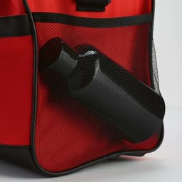 A red gym bag features black reflective strips and a mesh pocket holding a black drink bottle.