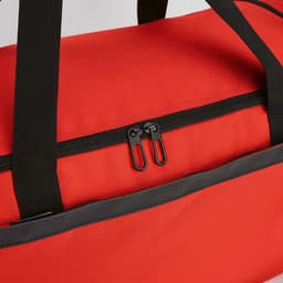 A red gym bag with a zip closure and black straps. It features reflective strips and has a logo.