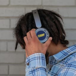 Headphones with a grey design and a circular blue logo are being worn by a person with dreadlocks.