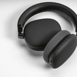 Black over-ear headphones with a textured grey cushion and control buttons, positioned on a white background.