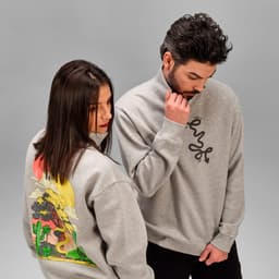 A grey 1/4 zipper sweatshirt made from organic cotton, featuring a design on the back and a logo on the front.