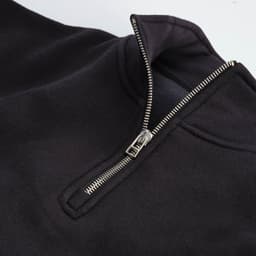 A black 1/4 zip sweatshirt made from organic cotton, rCotton, and rPET. Features a silver zipper and fabric collar.
