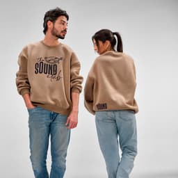 A beige oversized sweatshirt featured on two models, showcasing a logo on the front and back.