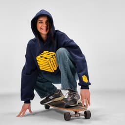 An oversized navy hooded sweatshirt with a logo, worn by a person squatting on a skateboard.