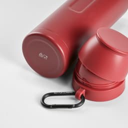 A drink bottle and two red cups, paired with a black carabiner. The bottle has a logo.
