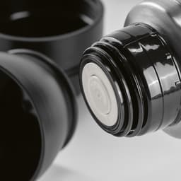 A drink bottle with a black finish, featuring a screw top and two cups included. It has a branding logo.