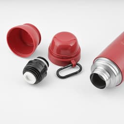 A drink bottle in red with a silver stainless steel body, featuring two cups and a black carabiner.