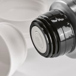 A drink bottle lid in black with white inner cap, accompanied by two white cups. The product includes a carabiner.