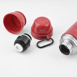 A drink bottle in red with a silver body, featuring two removable cups and a carabiner attachment.
