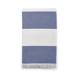 A striped towel featuring blue and white colours with fringe detailing, made in Portugal. It has a branding logo.