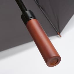 A brown handle of a black windproof umbrella with a sleek design and a logo on the handle.