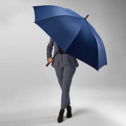 A windproof automatic umbrella in navy, held by a person in formal attire, featuring a wooden handle and a logo.