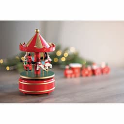 A red carousel music box featuring white horses, with a decorated canopy and a festive background of lights.