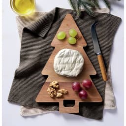 A wooden tree-shaped serving board featuring brie cheese, grapes, walnuts, and a knife, on a textured cloth.