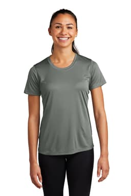 A smiling woman wearing a green Sport-Tek Ladies PosiCharge Competitor Tee and black leggings, standing with arms relaxed.