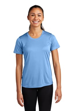 A woman in a blue athletic t-shirt stands smiling, featuring short sleeves and a comfortable fit. The shirt has a logo.