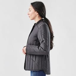 A black thermal jacket with a quilted design, featuring a collar and buttons, displayed on a model from the side.