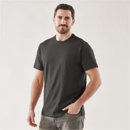 A man wearing a black short sleeve t-shirt, standing confidently with one hand in his pocket. The shirt has a logo.