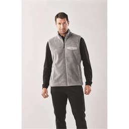 A grey men's fleece vest with a zip front and a logo on the chest, styled with a black long sleeve shirt.