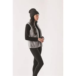 A woman wearing a grey Sherpa fleece vest with a black long-sleeve top and a black beanie, standing against a neutral background.
