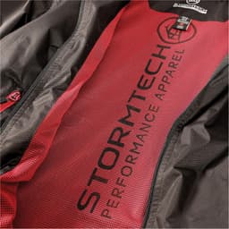 A black jacket with a red lining and mesh interior, featuring a logo and text.