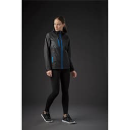 A woman wearing a black rain jacket with blue accents, paired with black leggings and sneakers.