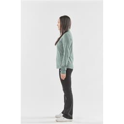 A side view of a woman wearing a teal performance jacket with long sleeves and black trousers.