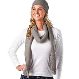 A woman wearing a grey knitted scarf and beanie, with her hair cascading down and a white long-sleeve top.