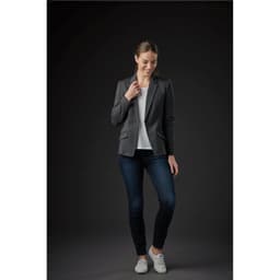 A women's Delano knit blazer in grey, paired with a light top and jeans, set against a dark background.