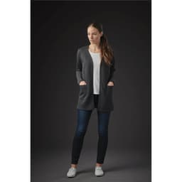 A woman wearing a dark grey Chelsea open cardigan over a white top, paired with dark jeans and casual white shoes.