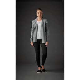 A woman wearing a grey Women's Soho Cardigan over a white top, paired with black leggings. The background is dark.