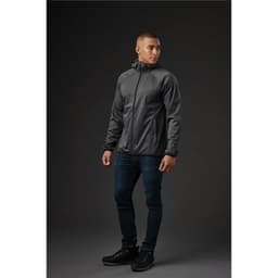 A man wearing a grey softshell jacket stands against a dark background, showcasing a sleek design and fitted style.