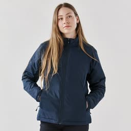 A woman wearing a navy blue thermal jacket with a zippered front and side pockets, featuring a logo.