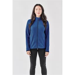 A woman wearing a full zip jacket in navy blue with a fitted design and a logo.